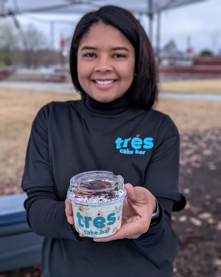 Natali at the market, holding up a tres leches cup